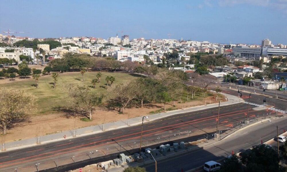 כביש ציר שלבים, לידו דשא ועצים ובניינים באופק